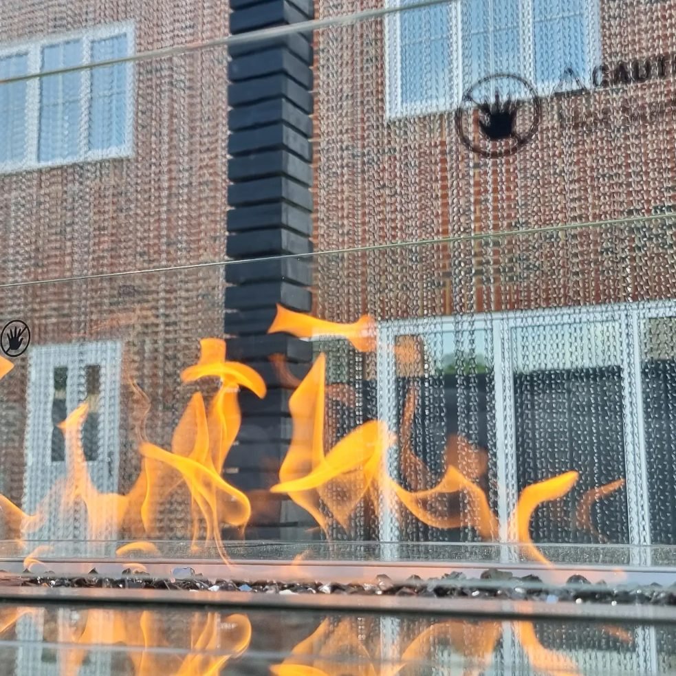 Close-up of flames in a fire table seen through its glass screen.